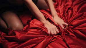 A woman clutching a red sheet